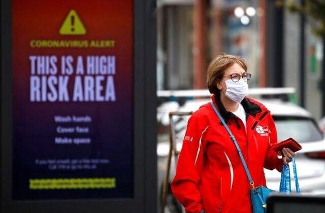 A woman walking past a billboard about covid 19 alert | Coronavirus New Strains Wreaking Havoc In Europe