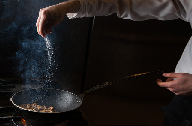 Chef sprinkling salt on sautéed mushroom | Types of Salt