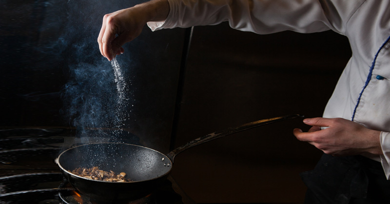 Chef sprinkling salt on sautéed mushroom | Types of Salt